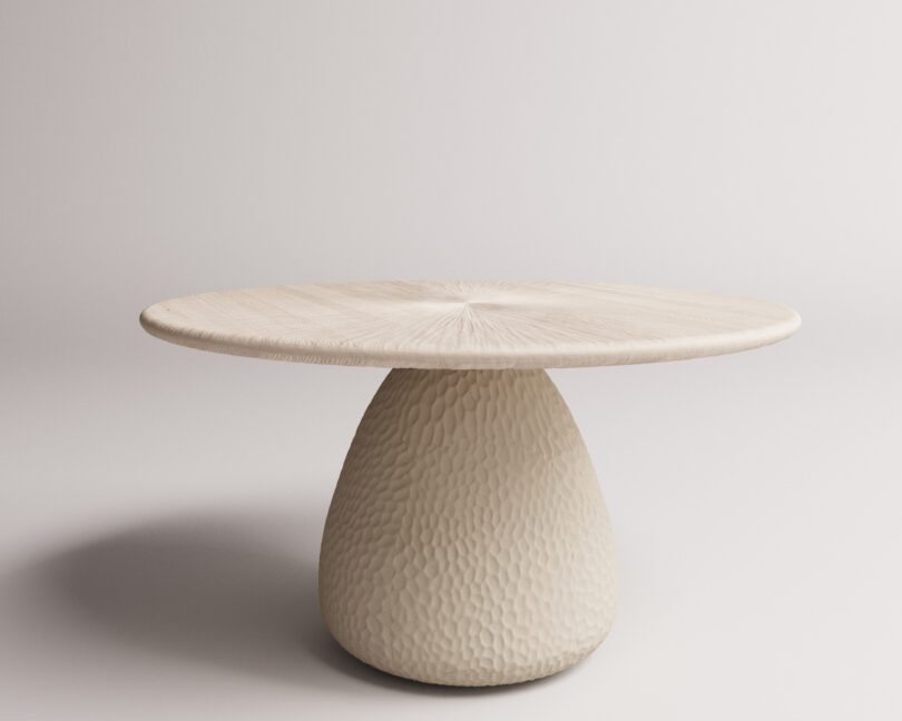 A round, textured table with a smooth top and a conical base, set against a plain white background