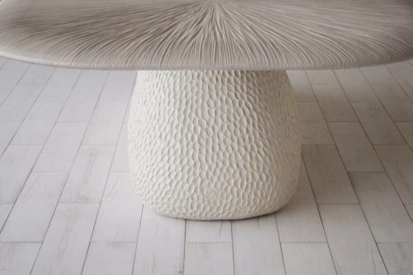 Close-up of a textured table with a white base and top, standing on a light wood floor