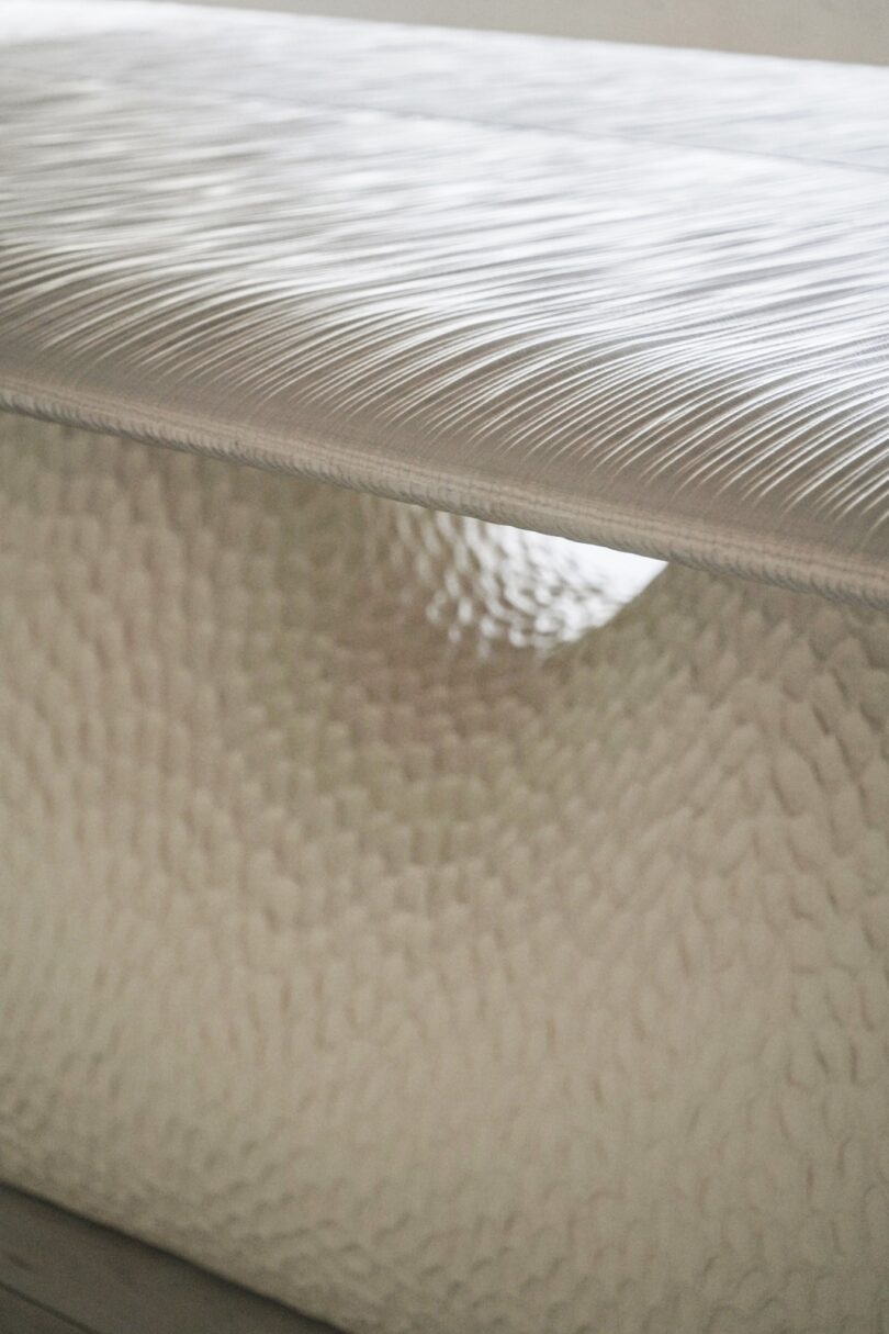 Close-up of a layered textured table with an abstract, wave-like pattern in shades of white