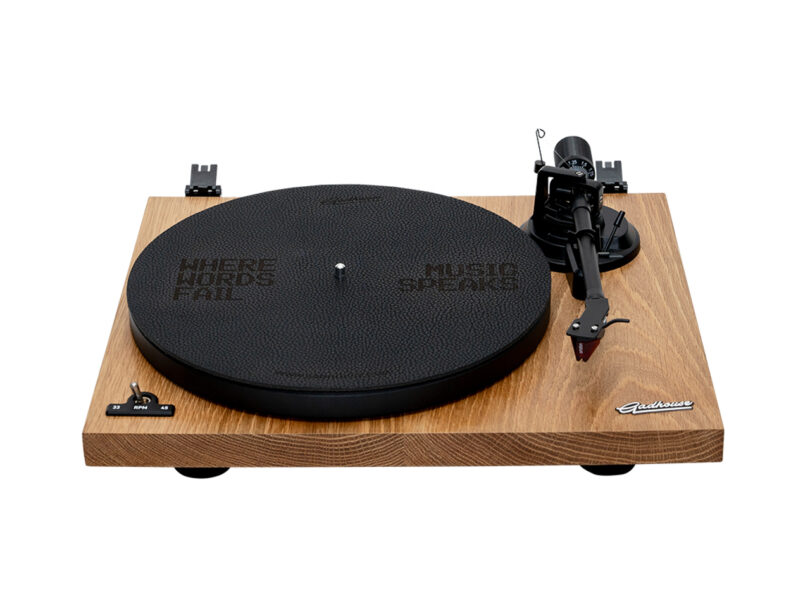 Wooden turntable with a black platter and tonearm. The platter displays the text "Where Words Fail Music Speaks.