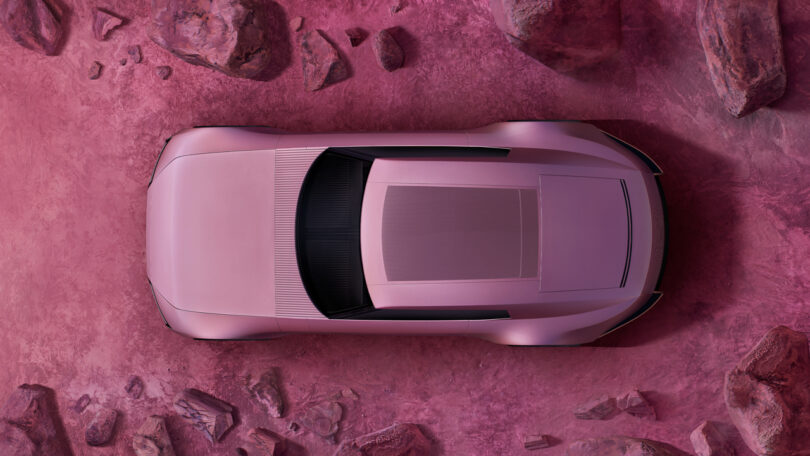 Top view of a pink sports car on a rocky, reddish-pink surface.