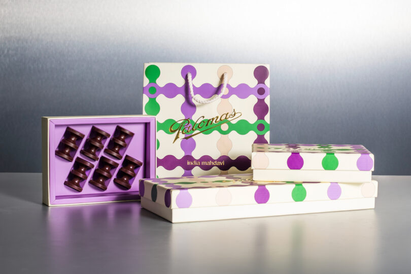 Gift bags and boxes with a purple and green polka dot design, displaying chocolates inside