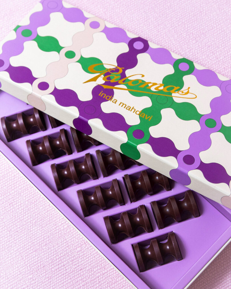 Box of neatly arranged chocolates with a colorful geometric patterned lid, featuring the text "india mahdavi"