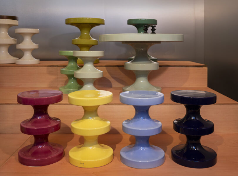 Assorted colorful ceramic stools and tables of varying heights displayed on wooden steps