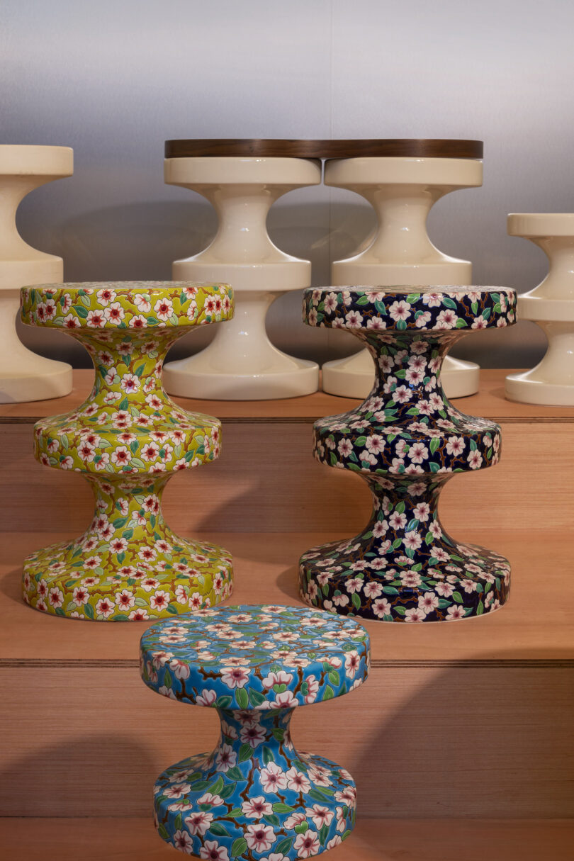 A display of stools featuring floral designs in various colors and plain cream ones, arranged on wooden steps