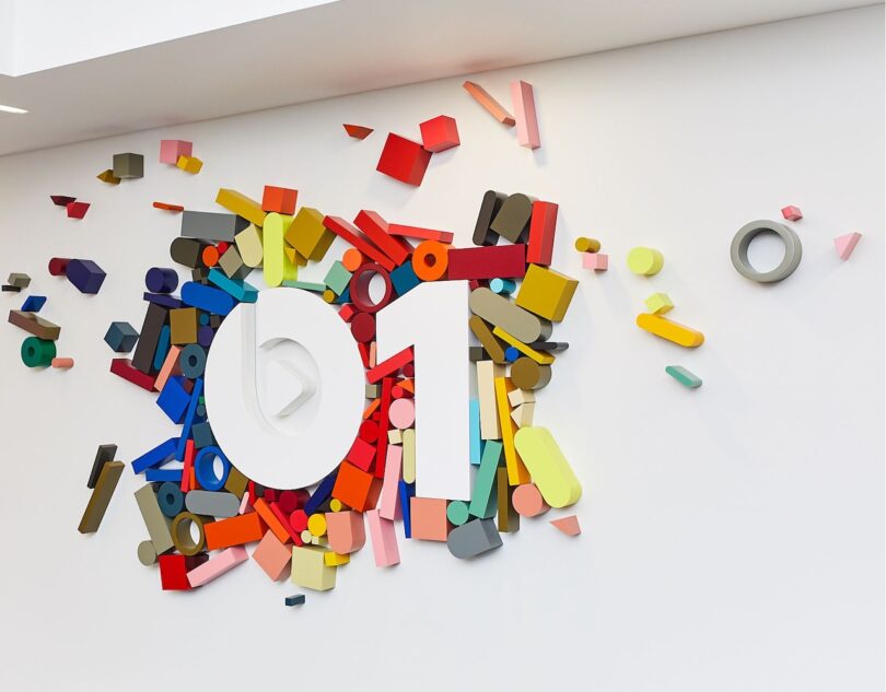 Colorful geometric shapes surround the number "01" on a white wall