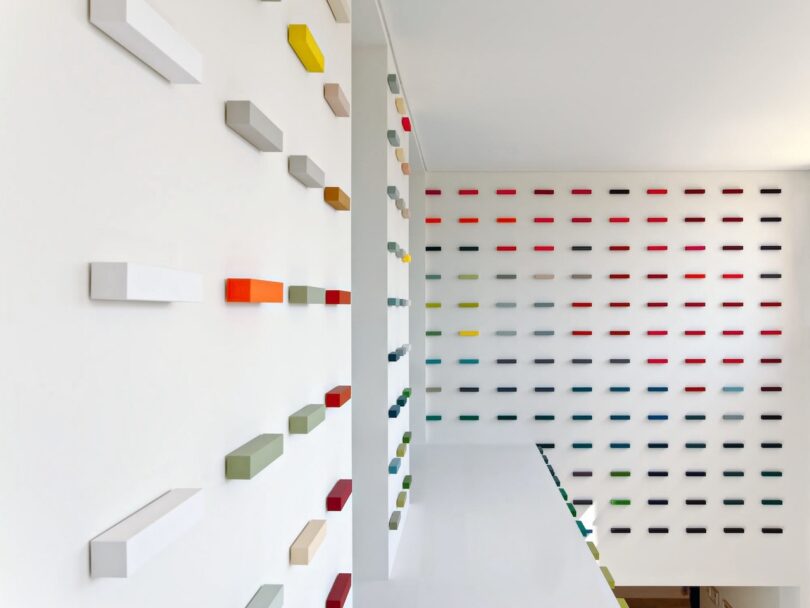 A modern art installation with colorful rectangular blocks protruding from white walls, creating an abstract pattern