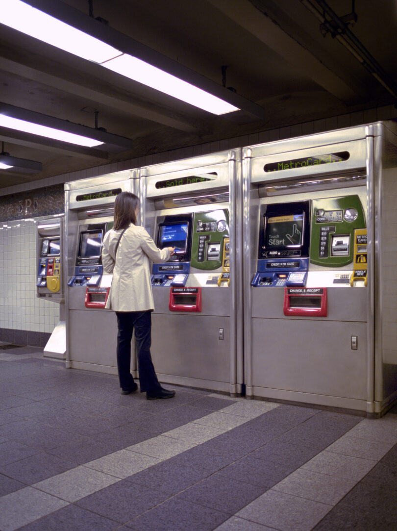 Woman, dressed in a white coat, navigates the busy subway station