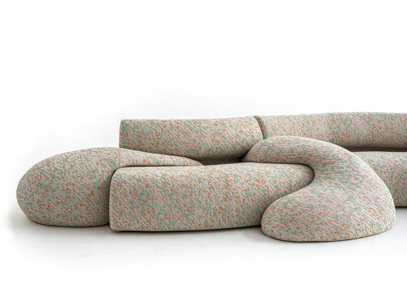 Modular, abstract-shaped sofa with a textured, multicolored fabric against a plain white background.