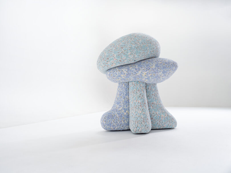 A sculptural object with a textured, abstract shape resembling mushrooms, featuring pastel colors on a smooth background.