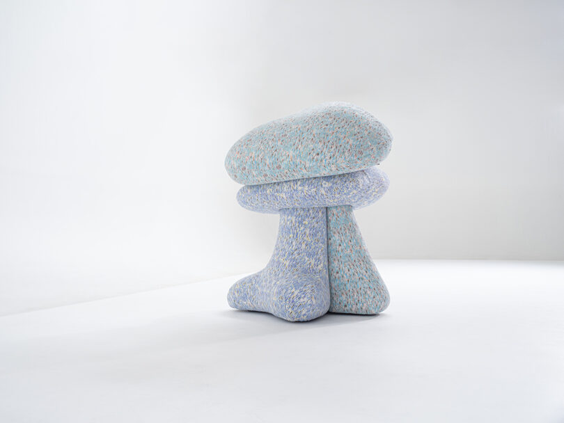 Two abstract, textured sculptures resembling mushroom shapes, one turquoise and one light purple, are placed on a plain white background.