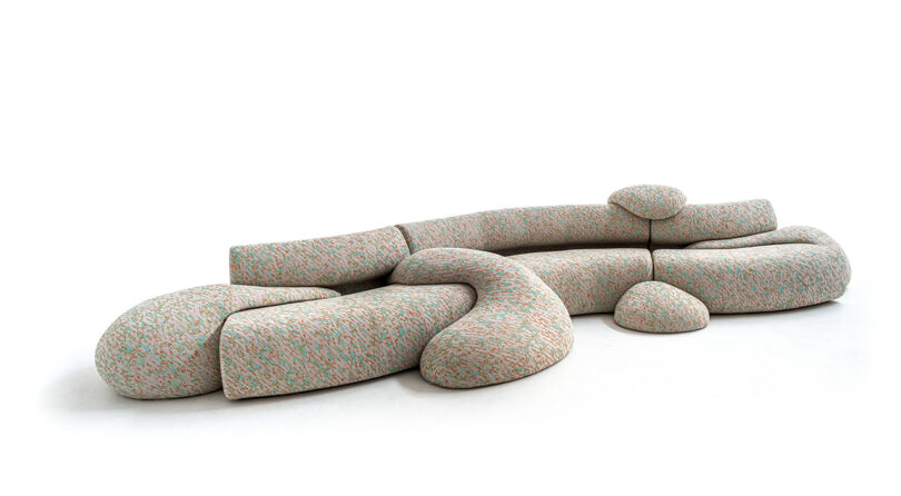 Modular sofa with abstract, curved shapes in a light fabric with splashes of color, arranged on a white background.