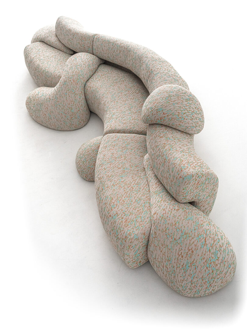 Abstract shaped, modular sofa with a textured, multicolored fabric, arranged in a flowing, undulating form on a white background.