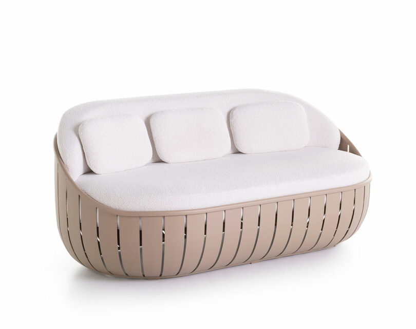 Modern sofa with a light beige woven base and white cushioned seat and backrest, featuring three small back cushions.