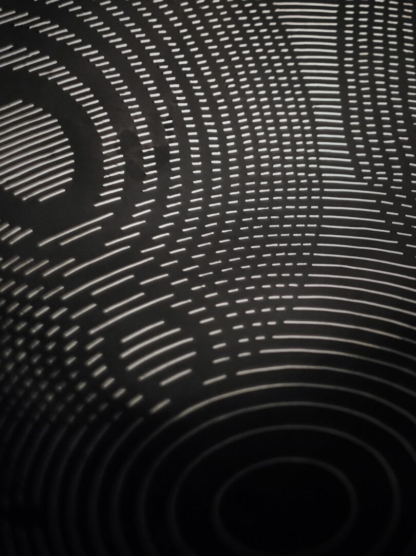 Abstract pattern featuring white curved and circular lines on a black background, creating an intricate, layered effect.