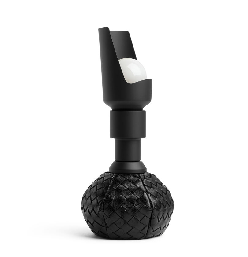 A modern table lamp with a black, textured base and an upward-facing light bulb.