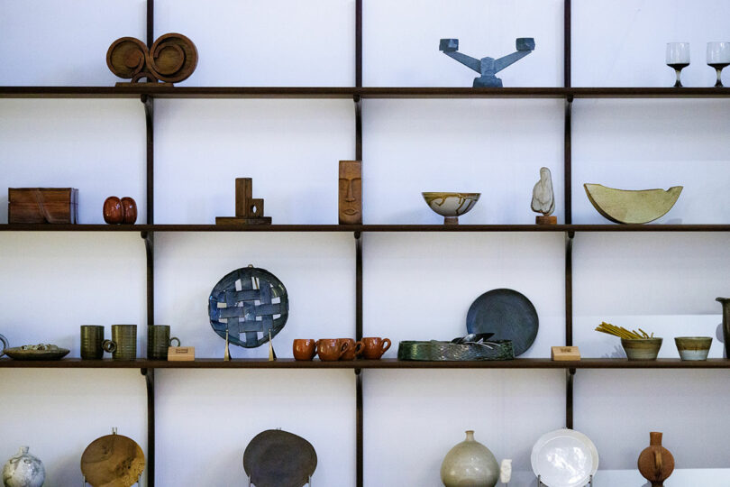 A wall of shelves featuring an array of decorative objects, including vases, bowls, sculptures, and ceramics, all tastefully arranged in a minimalist style reminiscent of CDW 2025 Product Awards displays.