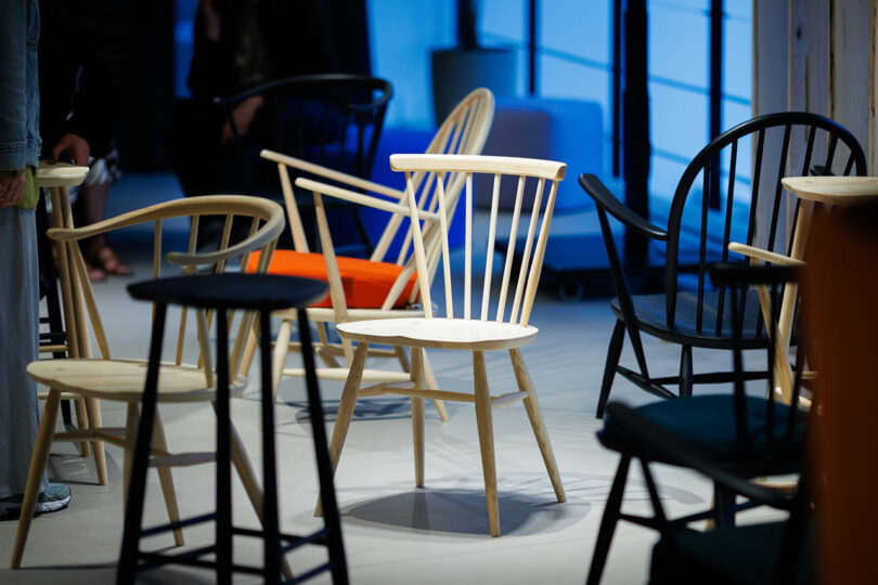 A group of wooden chairs in various designs and colors, all showcased in a well-lit room with a blue background, proudly highlight the innovative designs recognized at the CDW 2025 Product Awards.