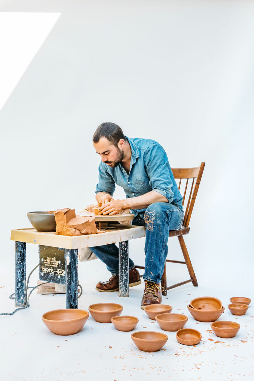 A person sits at a pottery wheel shaping clay, reminiscent of Alex Matisse's artistic influence, surrounded by finished bowls on the floor.