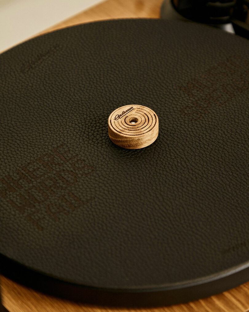 Close-up of a Gadhouse turntable with a textured surface, featuring a wooden record adapter in the center.