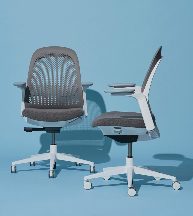 Two modern ergonomic office chairs with gray mesh backs and white frames, set against a light blue background.