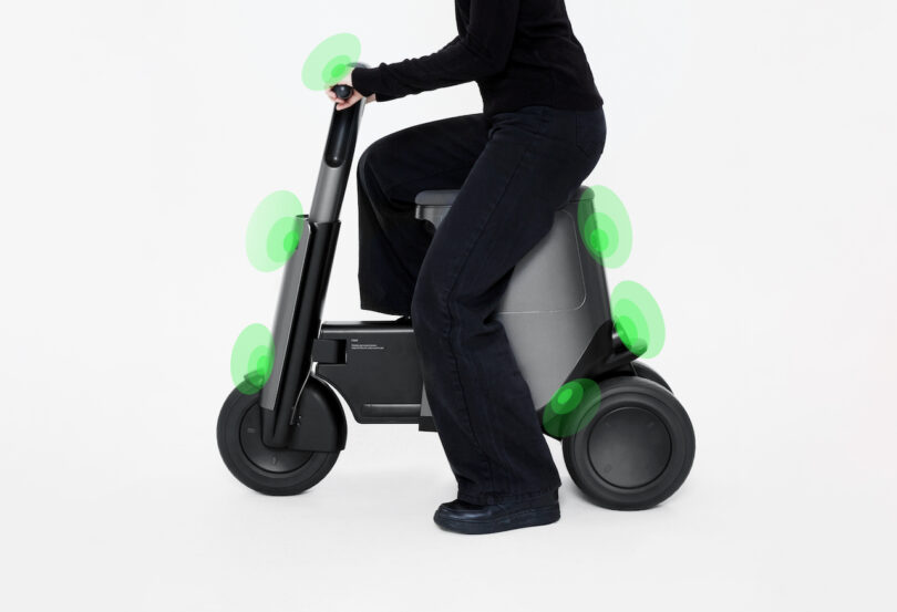 Person riding a compact electric scooter with highlighted areas indicating features or components.