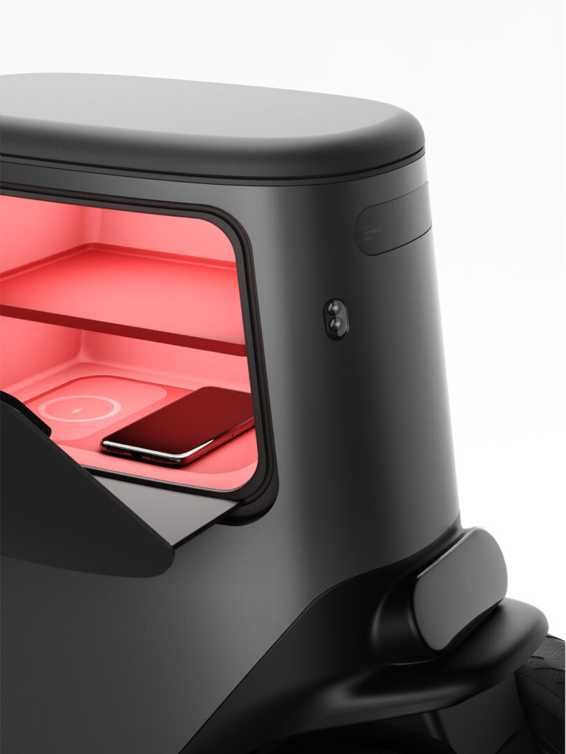 Close-up of a black robot storage compartment with a glowing red interior, holding a smartphone