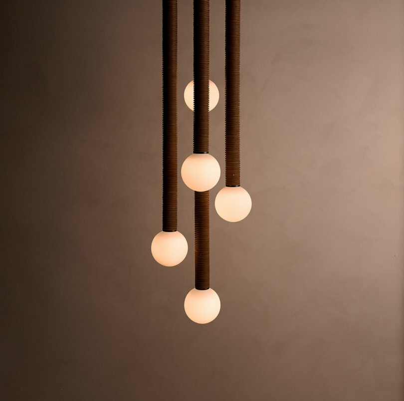 Five spherical pendant lights, reminiscent of Studio Luddite's minimalistic elegance, hang from the ceiling against a plain wall.