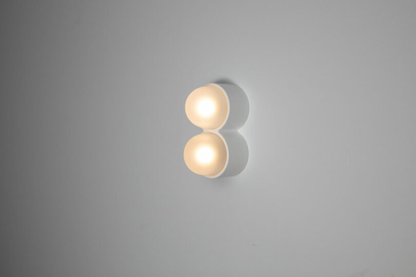 The Rider wall-mounted fixture features two round, overlapping lighted orbs against a plain background, embodying the minimalist elegance of Objects for Thought.