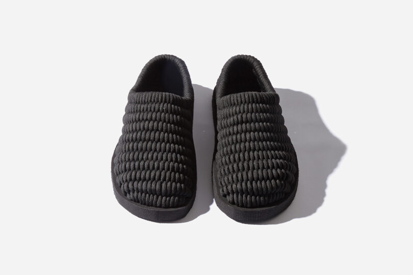 A pair of black textured slippers on a white background.