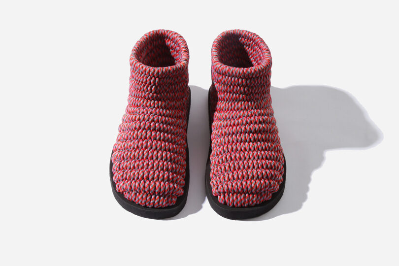 Pair of red and gray knitted slipper boots with black soles on a white background.