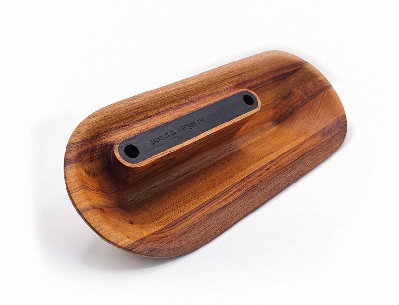 A wooden object with an oval shape, featuring a central, raised black strip with two holes.