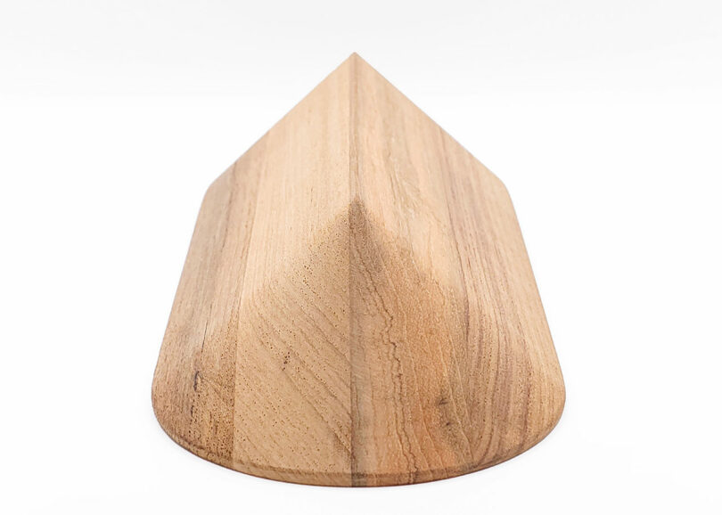 Wooden, triangular-shaped object with smooth surfaces and a natural wood grain pattern, resting on a flat surface.