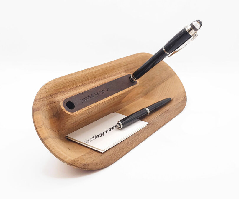 Wooden desk organizer holding a fountain pen, ballpoint pen, and business cards.