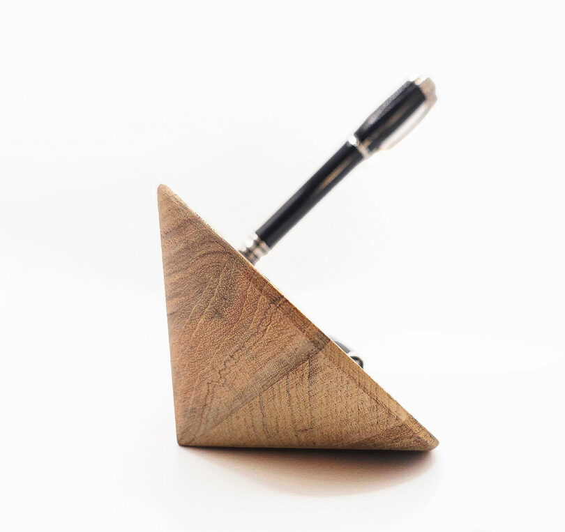 Pen resting in a triangular wooden holder on a white background.