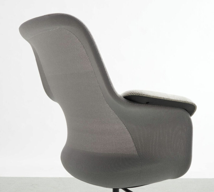 The back view of a Teknion gray office chair showcases its modern design, featuring a curved mesh backrest and cushioned seat, set against a plain white background.