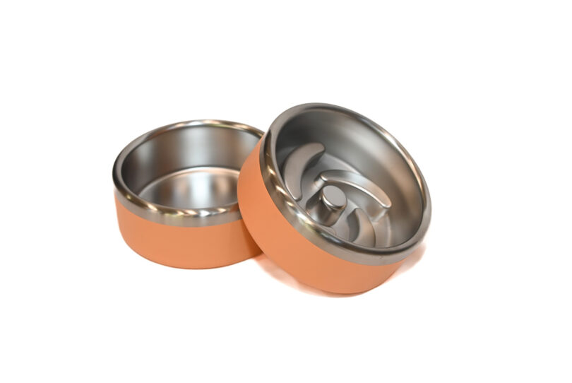 Two orange and silver mechanical parts, one laying sideways showing the interior, with curved structures inside.