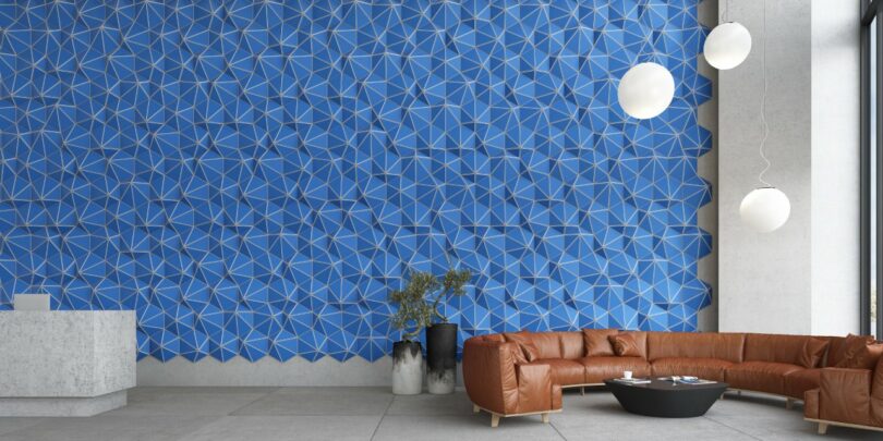 Modern room with a blue geometric accent wall, brown sectional sofa, round black table, white pendant lights, and a minimalistic reception desk.