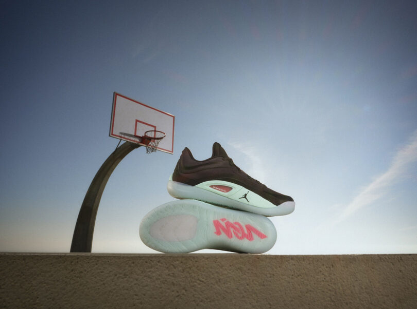 Une paire de baskets noires et blanches exposées près d'un panier de basket sous un ciel dégagé.