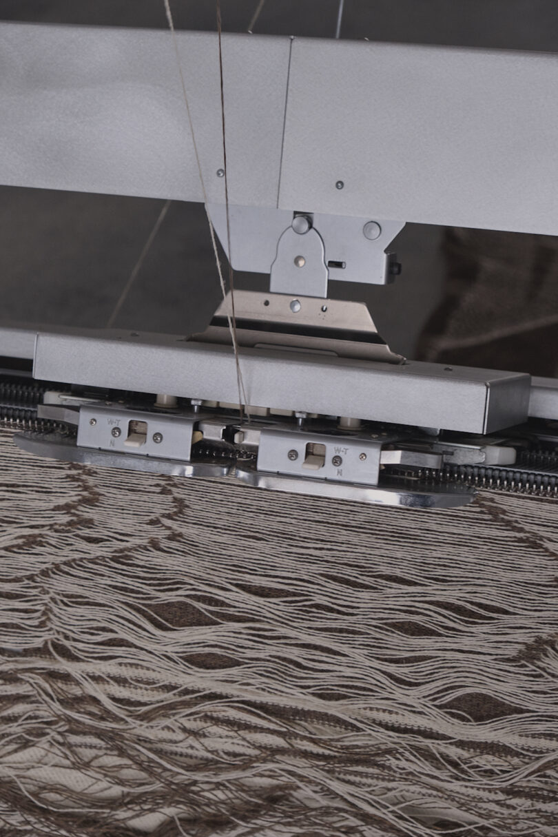 Close-up of a textile machine weaving intricate patterns with brown and beige thread