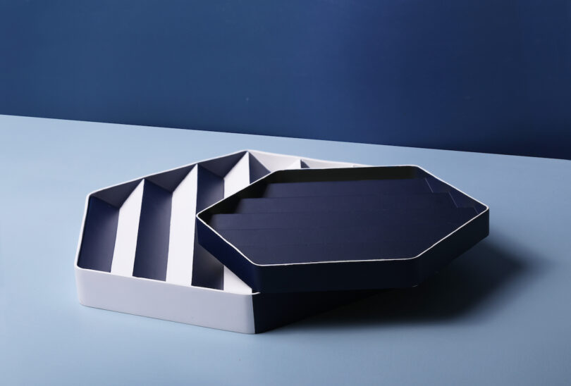 Hexagonal navy blue and white boxes with lids open, set against a two-tone blue background