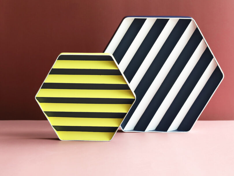 Two hexagonal plates against a reddish background. One plate is yellow with black horizontal stripes, and the other is black and white with diagonal stripes