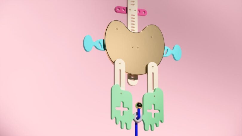 Abstract necklace with pastel colors, featuring a gold metallic center, arms with blue elements, and legs with green shapes on a pink background.