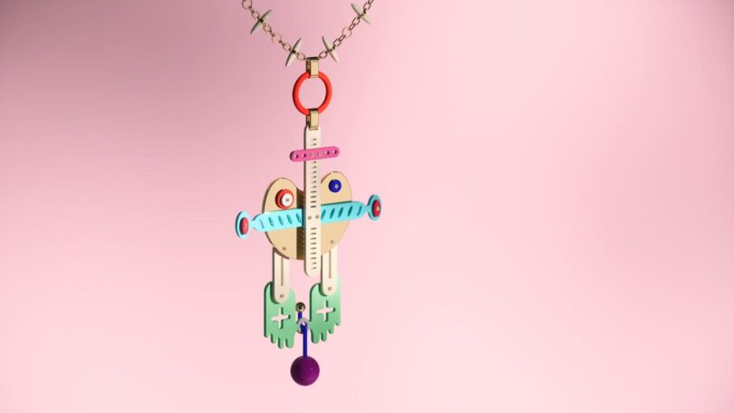 Colorful abstract pendant with geometric shapes, featuring a purple bead, green and pink components, and blue details, set against a light pink background