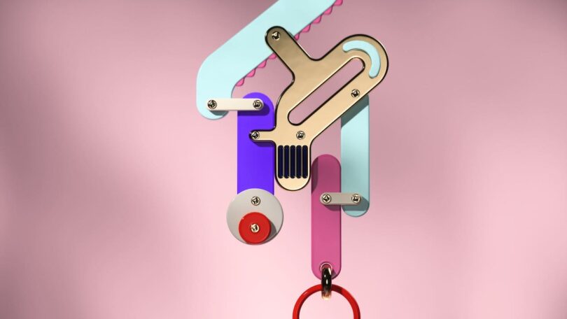 A colorful abstract earring with geometric shapes against a pink background.