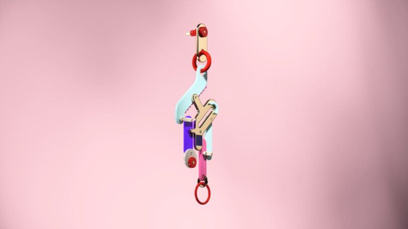 A colorful abstract earring with geometric shapes against a pink background.