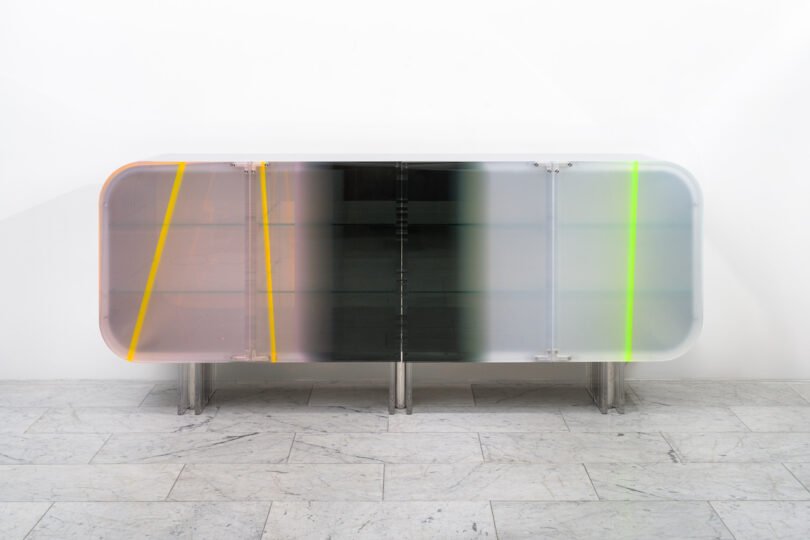 A modern, translucent sideboard with a rounded design, featuring colorful panels in shades of orange, pink, green, and gray, set against a light background