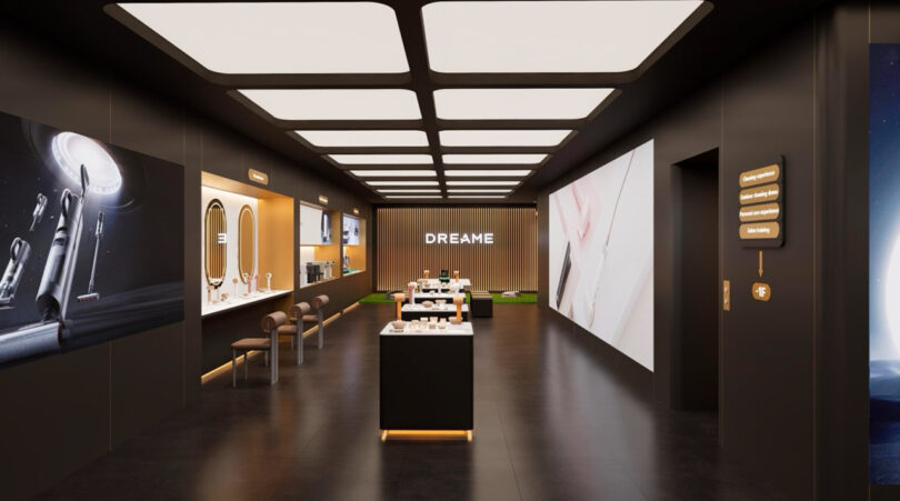 Modern showroom with sleek black and white design, showcasing electronic products. Large displays and seating area are present. Warm lighting enhances the contemporary atmosphere.