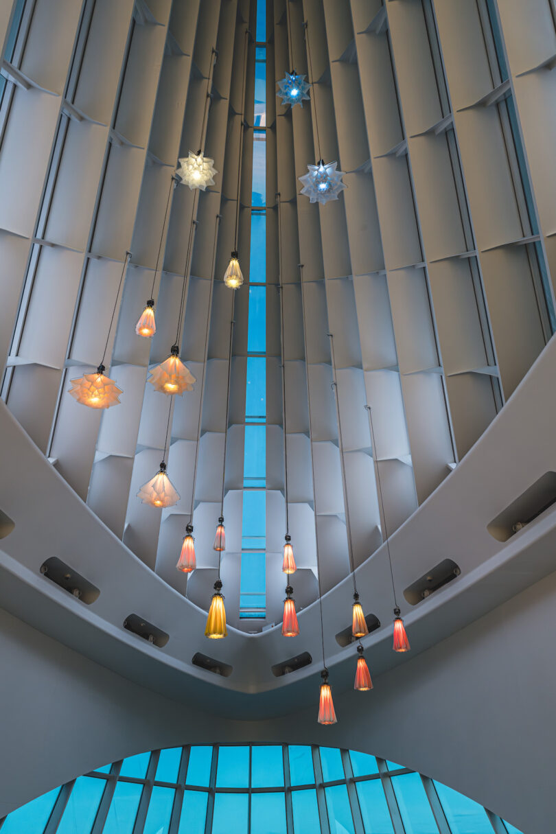 hanging kinetic flowers in a modern, white-walled gallery with a geometric ceiling.