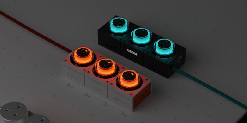 Two modular power strips with glowing sockets; one with orange light, the other with teal. Each has three plug sockets and is connected via colored cables.